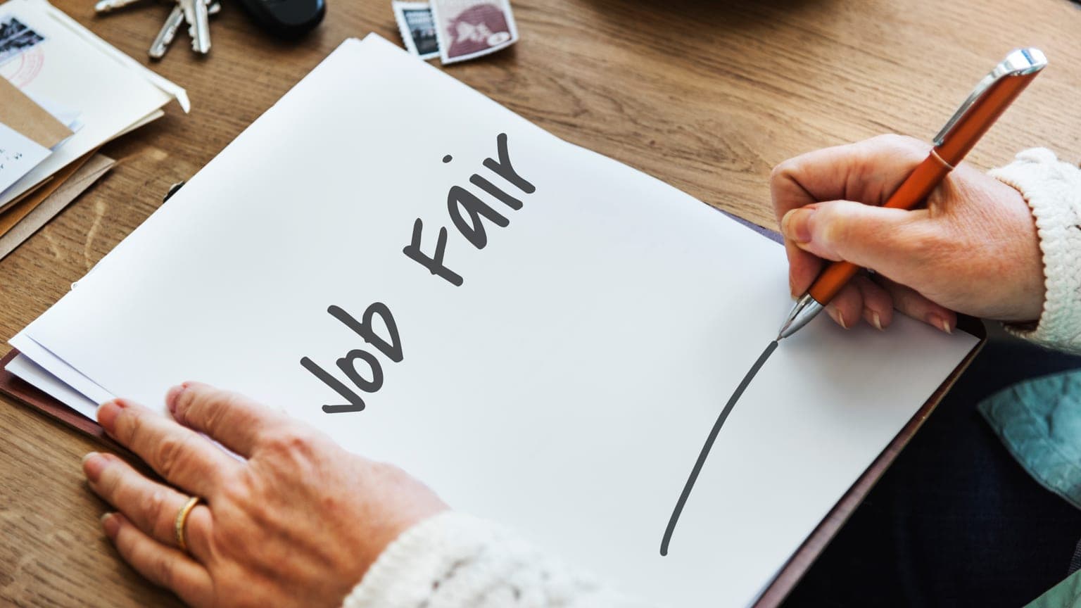 Ruka píše nadpis Job Fair na papír — kde hledat volná pracovní místa